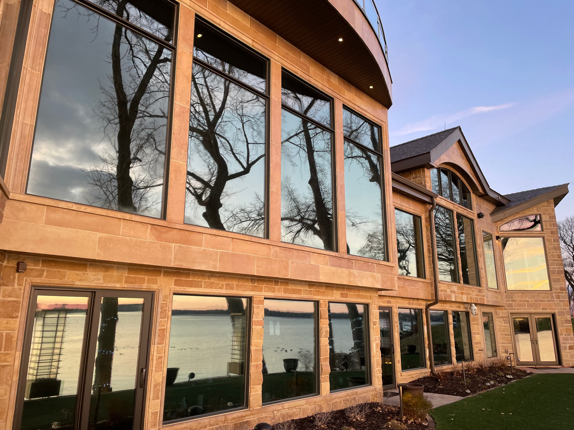 Lake home with every window sparkling clean at sunset, reflecting the sky in the glass